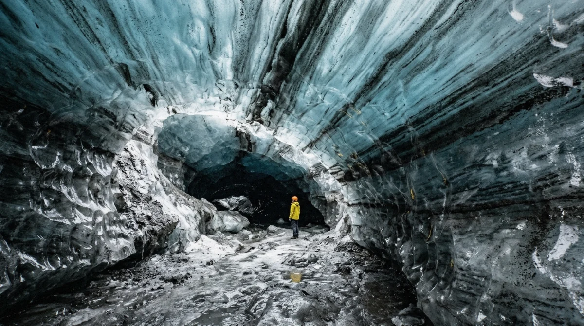 Black volcanic ash bands folded through blue ice on the roof of the Katla ice cave inside Kötlujökull, Iceland
